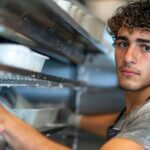 Jeune homme lavant vaisselle dans cuisine professionnelle